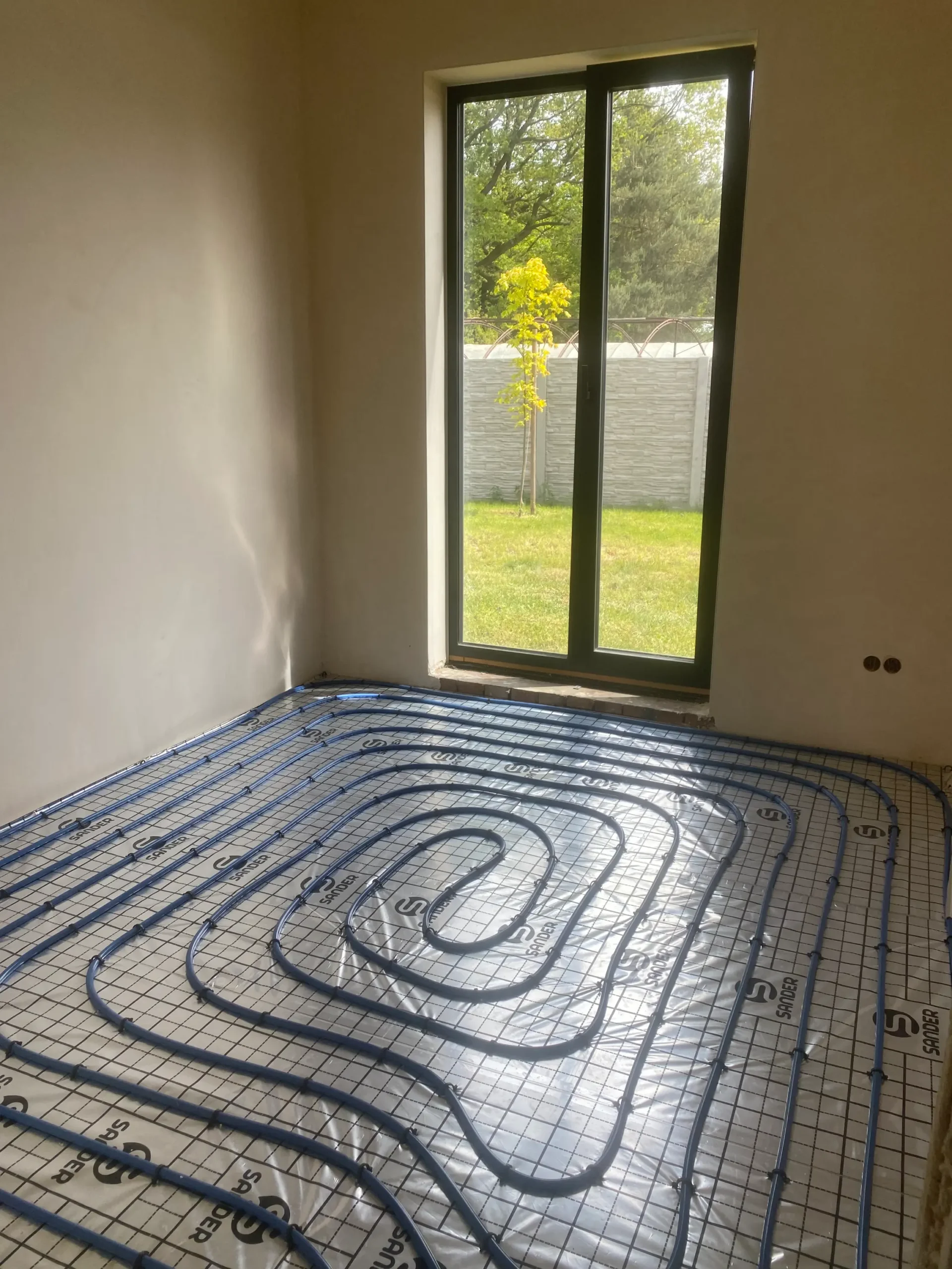 Widok na przygotowane ogrzewanie podłogowe w pomieszczeniu przed położeniem wylewki, widoczna sieć przewodów