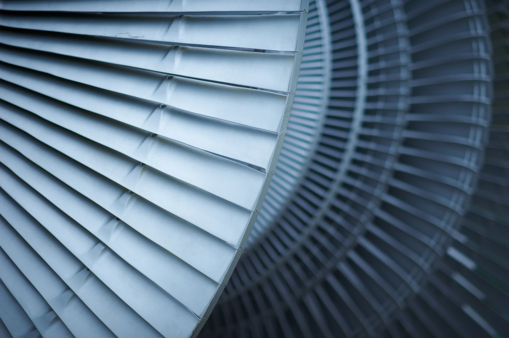 Zbliżenie na metalowy wirnik wentylatora systemu Rekuperacja z poziomo ułożonymi łopatkami