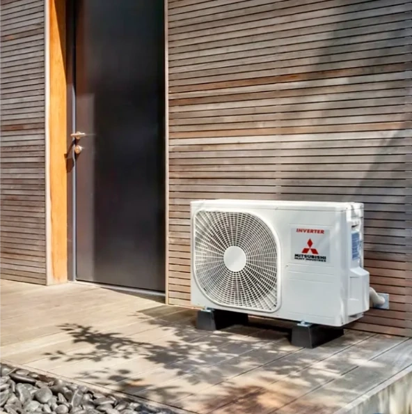 Jednostka zewnętrzna pompy ciepła zamontowana na tarasie przy drewnianej elewacji