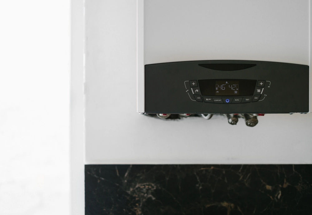 Nowoczesny ścienny kocioł gazowy z panelem cyfrowym na białej ścianie – Wymiana pieca